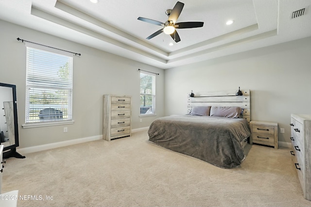 bedroom with visible vents, a raised ceiling, baseboards, and light carpet