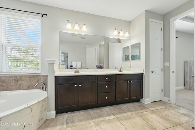 bathroom featuring tile patterned flooring, a garden tub, double vanity, and a sink