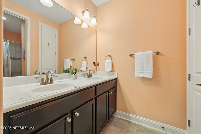 bathroom with double vanity, tile patterned flooring, baseboards, and a sink