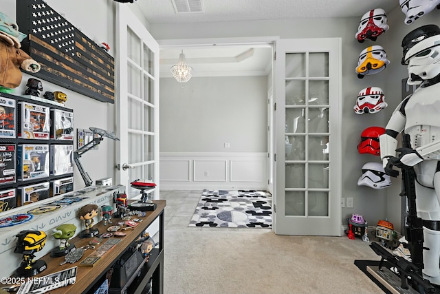 office area featuring carpet, visible vents, french doors, wainscoting, and a decorative wall