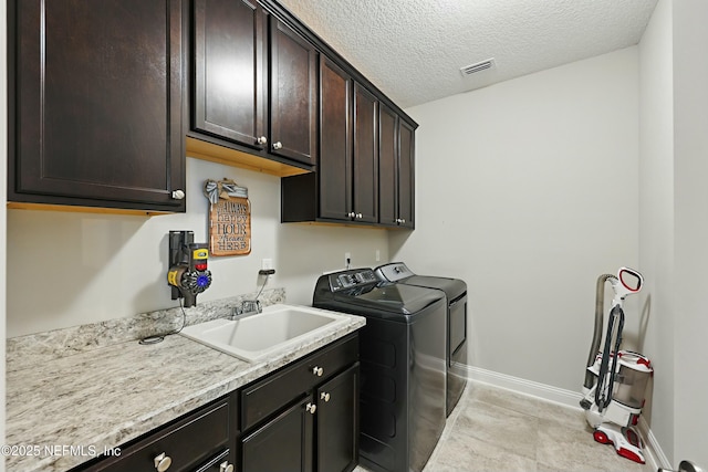 laundry area with visible vents, a sink, a textured ceiling, cabinet space, and washing machine and clothes dryer