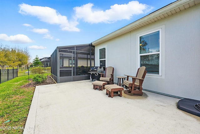 view of patio featuring a lanai, grilling area, and fence