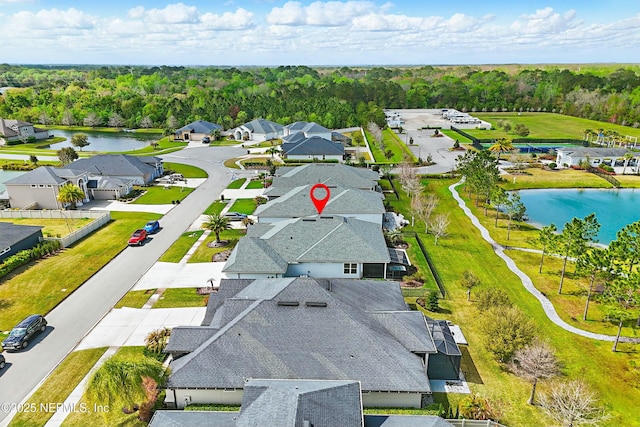 birds eye view of property with a residential view, a water view, and a view of trees