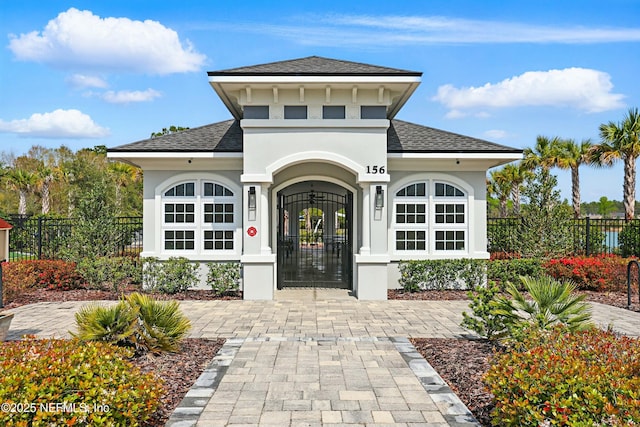 doorway to property with fence, roof with shingles, and stucco siding