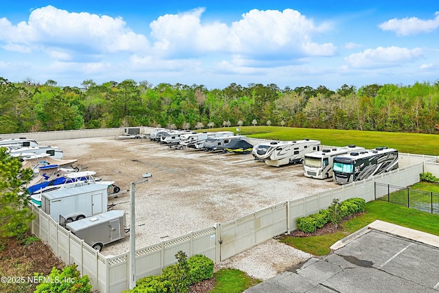 uncovered parking lot with a view of trees and fence