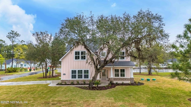 view of front of house with stone siding, board and batten siding, and a front lawn