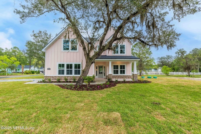 view of front facade featuring board and batten siding, a front lawn, and stone siding