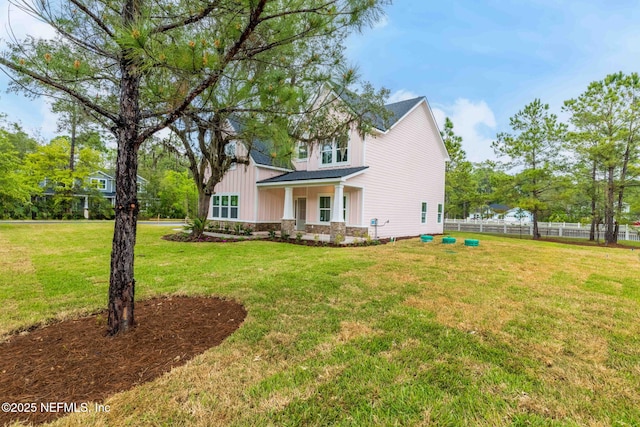 exterior space featuring a front lawn, fence, and stone siding