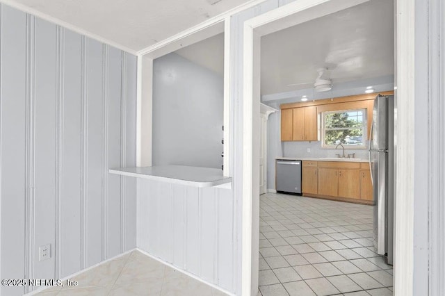 kitchen with a ceiling fan, a sink, appliances with stainless steel finishes, light countertops, and light tile patterned floors