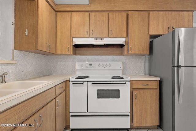 kitchen with under cabinet range hood, a sink, freestanding refrigerator, white range with electric stovetop, and light countertops