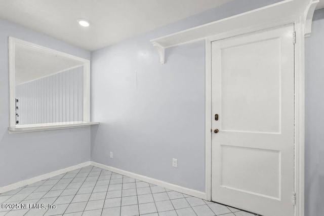 spare room featuring light tile patterned flooring and baseboards