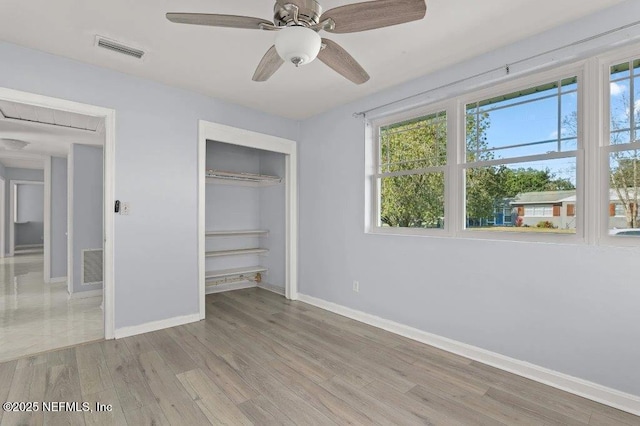 unfurnished bedroom featuring a closet, visible vents, baseboards, and wood finished floors