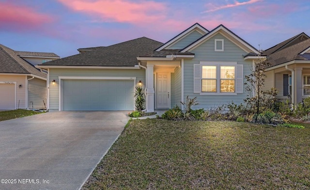 view of front facade featuring a shingled roof, concrete driveway, a garage, and a front yard