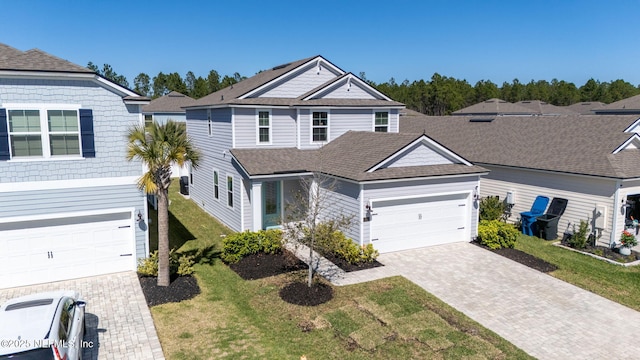 view of front of property with decorative driveway, a front yard, and roof with shingles