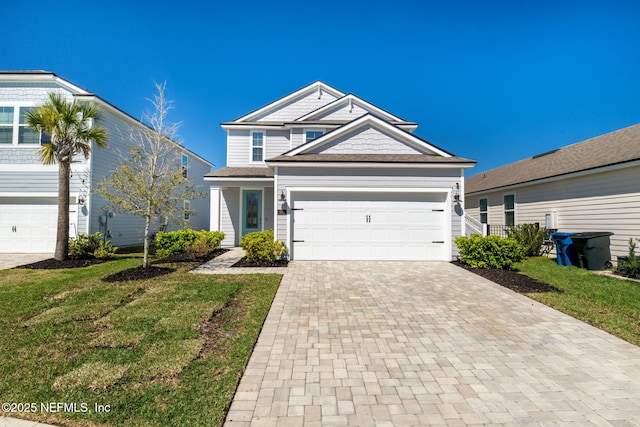 traditional-style home with a garage, decorative driveway, and a front yard