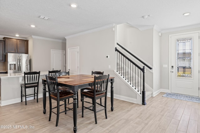 dining space with baseboards, stairway, ornamental molding, light wood-style floors, and a textured ceiling