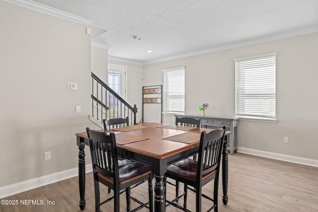 dining space featuring baseboards, light wood-style flooring, and ornamental molding