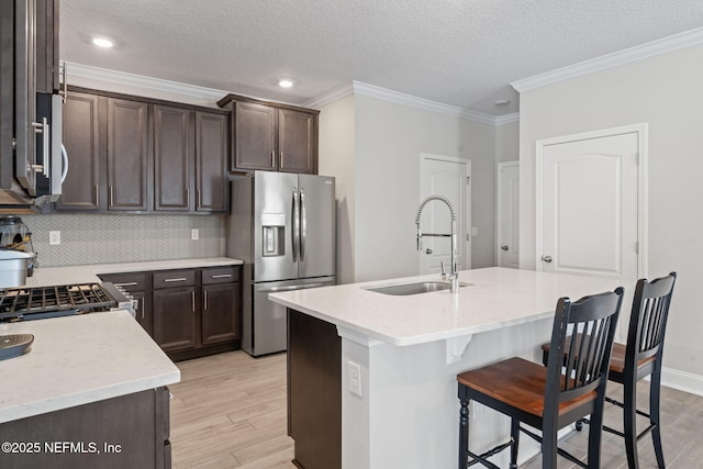 kitchen featuring dark brown cabinetry, light wood-type flooring, appliances with stainless steel finishes, and a sink