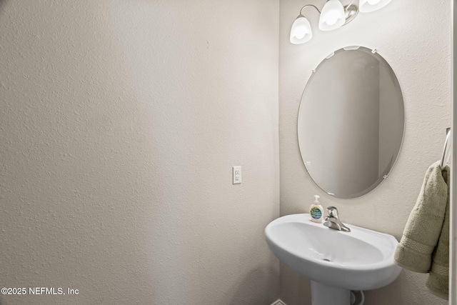 bathroom featuring a sink and a textured wall