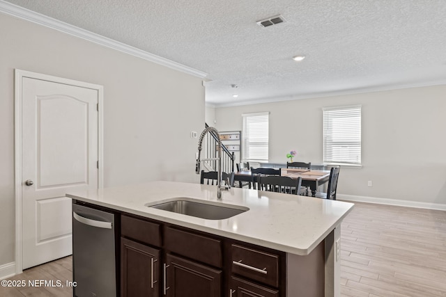 kitchen featuring visible vents, a sink, dishwasher, light wood-type flooring, and a kitchen island with sink