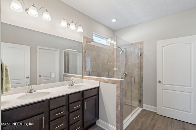 full bath with a sink, wood finished floors, a stall shower, and double vanity