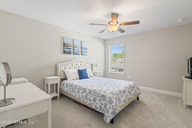 bedroom with ceiling fan, light colored carpet, baseboards, and a textured ceiling