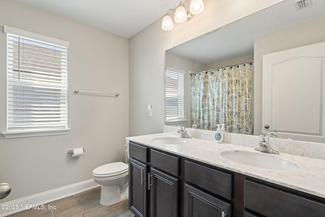 full bath featuring toilet, baseboards, visible vents, and a sink