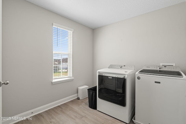 laundry room with laundry area, a healthy amount of sunlight, light wood-type flooring, and washer and clothes dryer