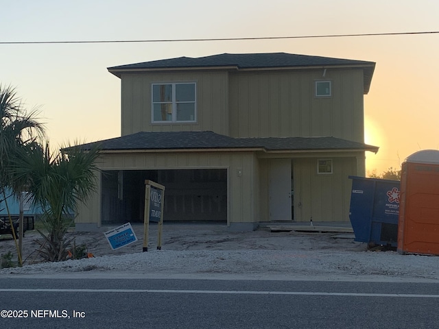 view of front of home featuring an attached garage, board and batten siding, driveway, and roof with shingles