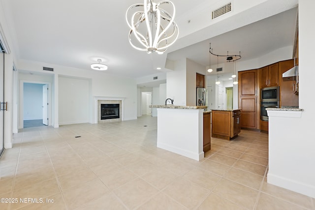 kitchen featuring stainless steel appliances, brown cabinets, visible vents, and open floor plan