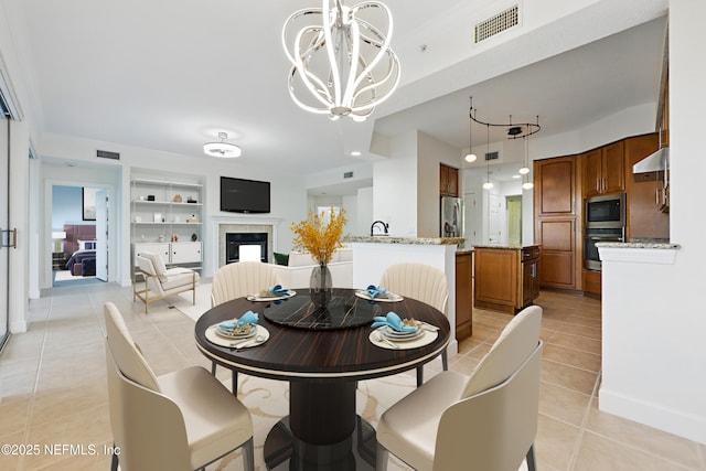 dining space with a tiled fireplace, light tile patterned floors, visible vents, and built in shelves