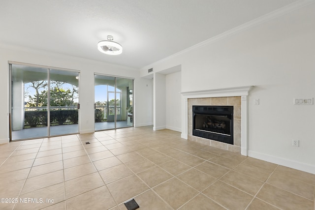 unfurnished living room featuring tile patterned floors, a tiled fireplace, crown molding, and baseboards