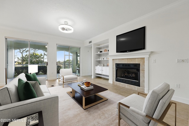 living area featuring ornamental molding, a tiled fireplace, built in features, light tile patterned floors, and baseboards