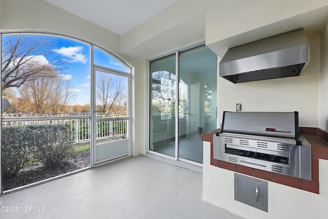 kitchen with finished concrete flooring, wall chimney exhaust hood, and a textured wall