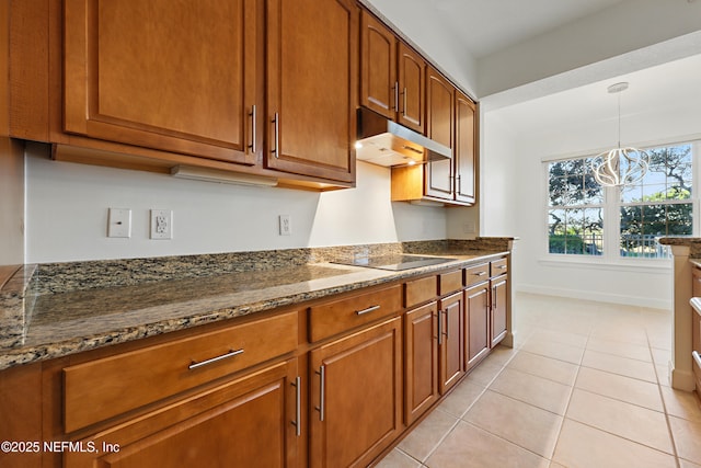 kitchen featuring under cabinet range hood, black electric cooktop, brown cabinets, and light tile patterned floors