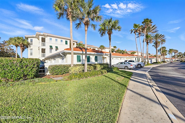 view of front of property featuring stucco siding, a front yard, and a tiled roof