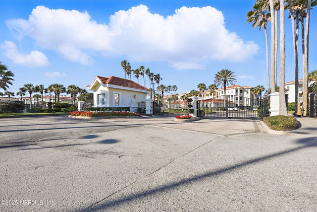 view of road featuring a gate, curbs, a residential view, and a gated entry