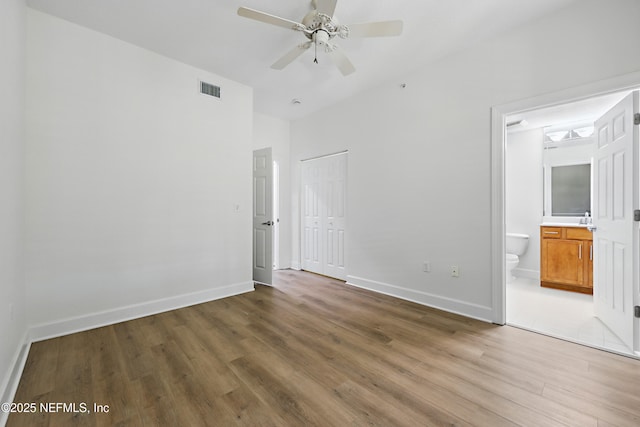 unfurnished bedroom with baseboards, visible vents, light wood-style flooring, a closet, and ensuite bathroom