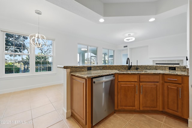 kitchen featuring a sink, decorative light fixtures, dark stone counters, brown cabinetry, and dishwasher