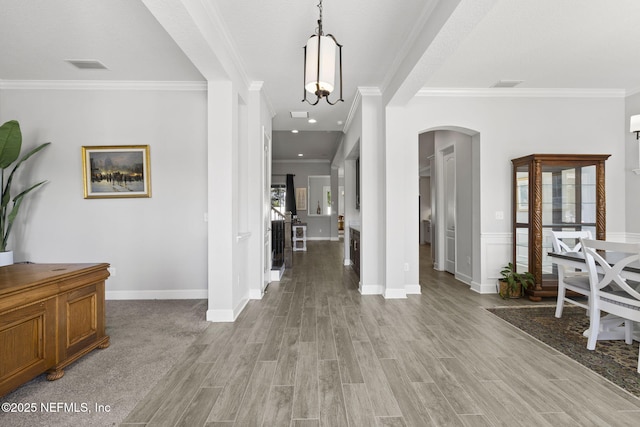 foyer entrance featuring visible vents, arched walkways, crown molding, and light wood finished floors