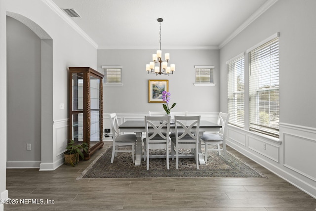 dining space featuring wood finished floors, visible vents, arched walkways, ornamental molding, and a notable chandelier