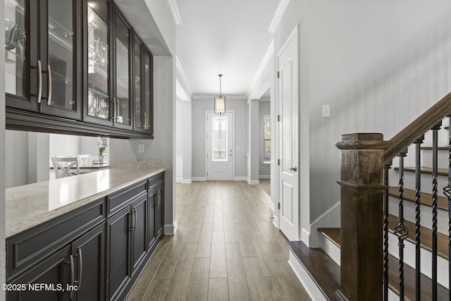 corridor featuring stairway, dark wood-style floors, baseboards, and ornamental molding