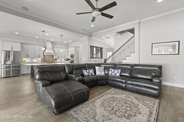 living area with light wood finished floors, crown molding, baseboards, recessed lighting, and a ceiling fan