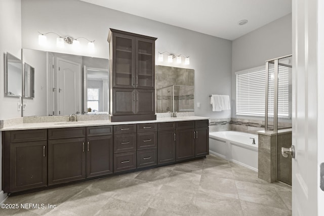 bathroom featuring double vanity, a garden tub, a stall shower, and a sink