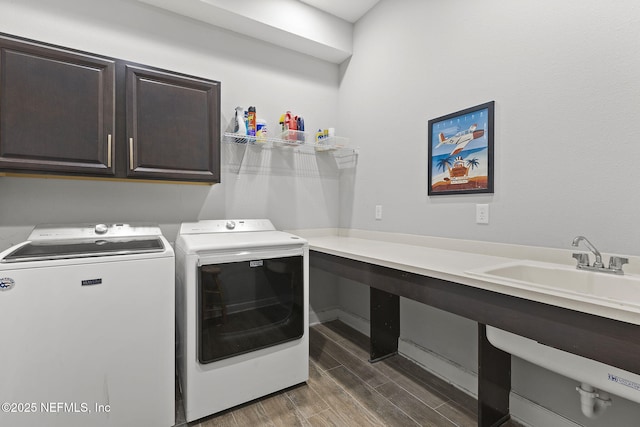 clothes washing area with washer and dryer, cabinet space, wood tiled floor, and a sink