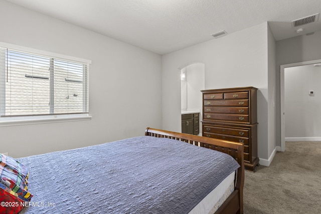 bedroom with visible vents, baseboards, carpet, arched walkways, and a textured ceiling