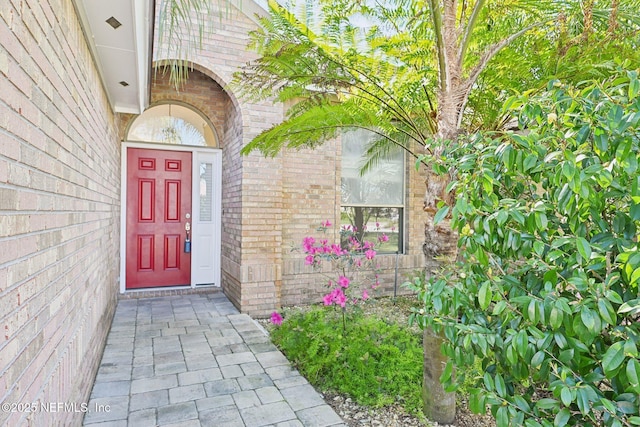 view of exterior entry featuring brick siding