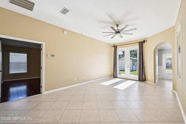 unfurnished room featuring visible vents, arched walkways, a ceiling fan, and french doors