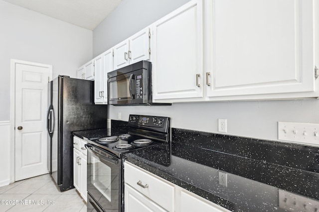 kitchen featuring black appliances, white cabinets, light tile patterned floors, and dark stone counters