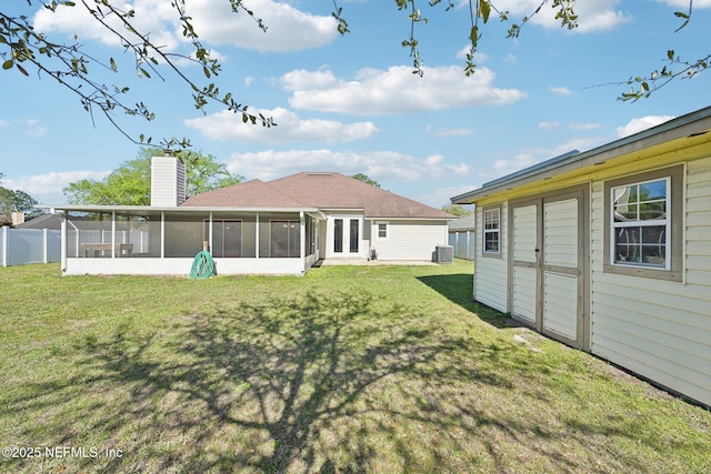 rear view of property featuring a lawn, central AC, fence, a sunroom, and a chimney